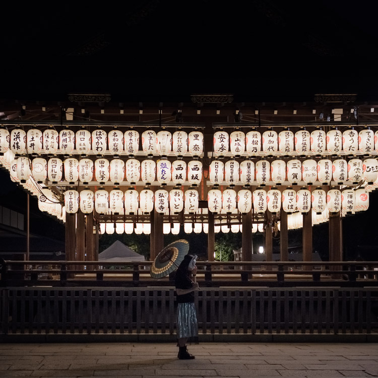 In front of a display of lanterns bearing the names of generous temple donors, a young woman dawns a rabbit mask. In local folklore, the rabbit committed along with other creatures to practice charity on the day of the full moon. Only knowing how to gather grass, the rabbit offered up itself. Recognized for this virtuous action its likeness was said to be drawn upon the moon.