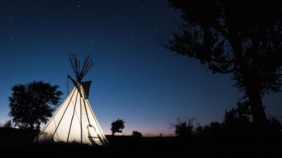 A teepee lit up against the tapestry of the night sky.Context: A scene from the dark sky preserve that is Grasslands National park. –link forthcoming–